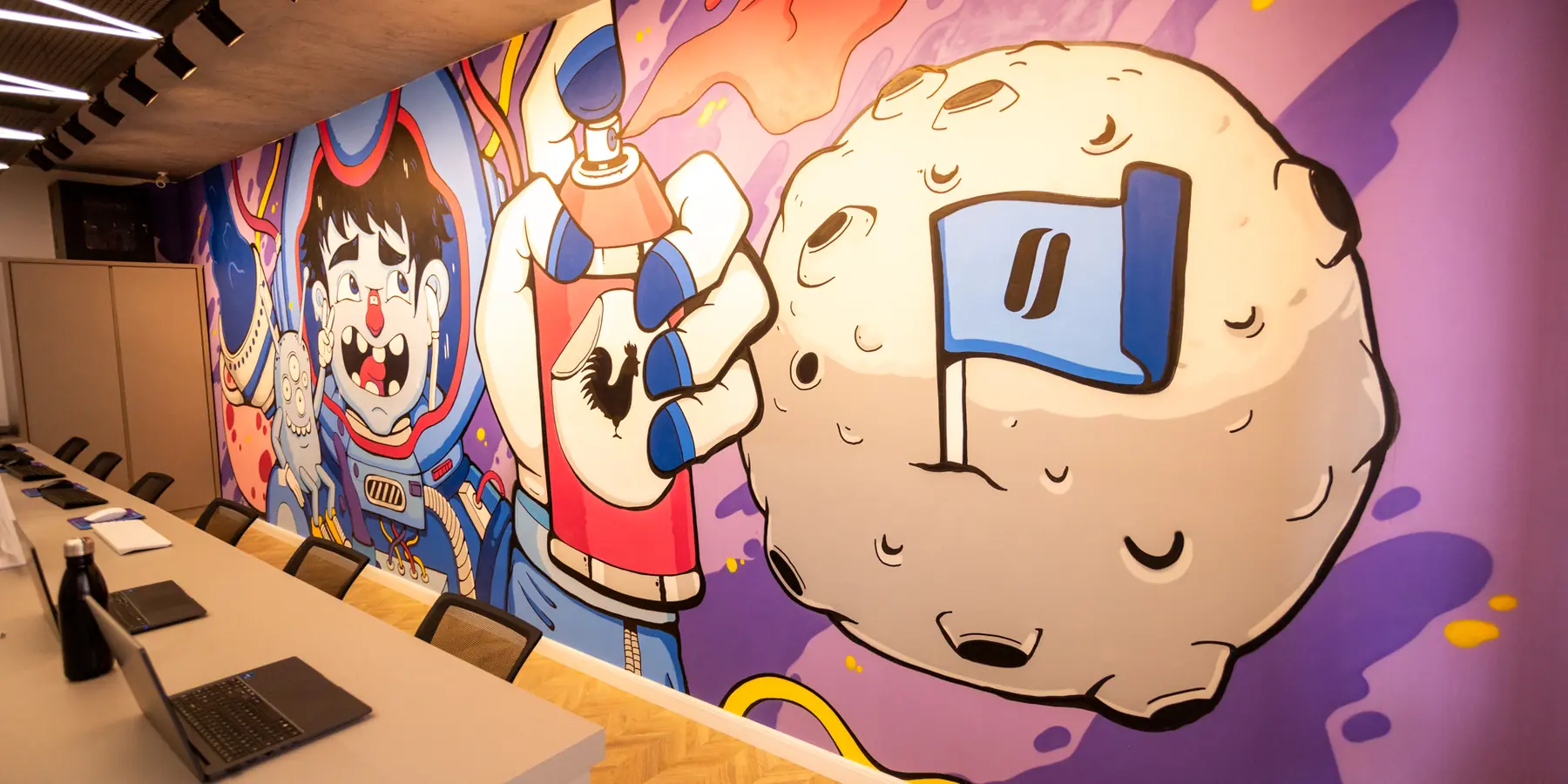 Mesas de trabalho da criação da Moinho ao lado do mural grafitado