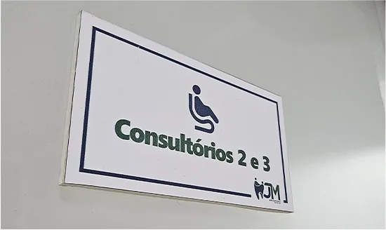 Placa de sinalização interna da JM indicando os consultórios 2 e 3, com ícone de acessibilidade