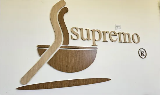 Símbolo do Supremo Café em MDF cortado a laser, com acabamento em laminado amadeirado, aplicado internamente