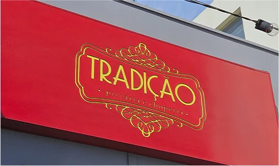 Detalhe do painel de fachada da Tradição, com o brasão do logotipo iluminado internamente